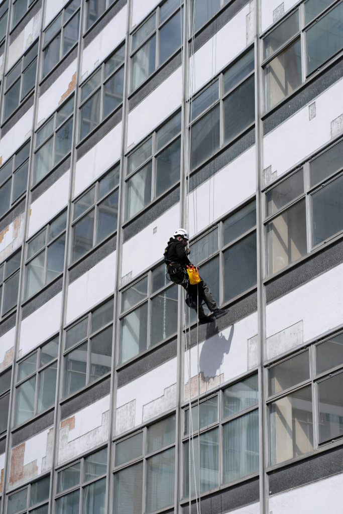 man in black jacket and black pants standing in front of glass window building during daytime